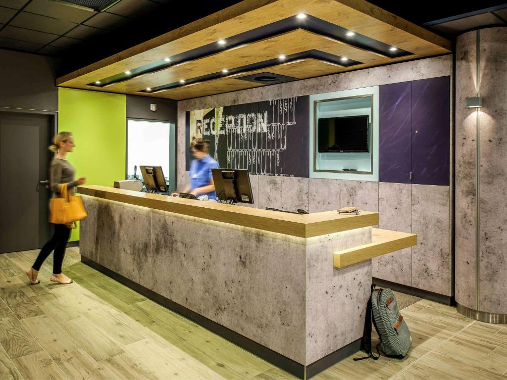 a woman standing in front of a reception desk at ibis budget Strasbourg La Vigie in Ostwald