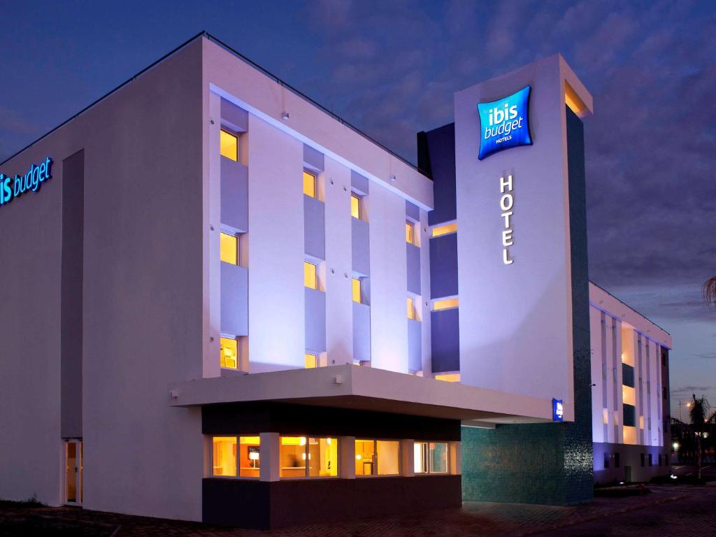 un edificio de hotel iluminado con un cartel en Ibis Budget Montbéliard, en Montbéliard