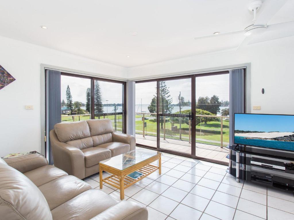 a living room with a couch and a tv at Oxley 8 at Tuncurry in Tuncurry