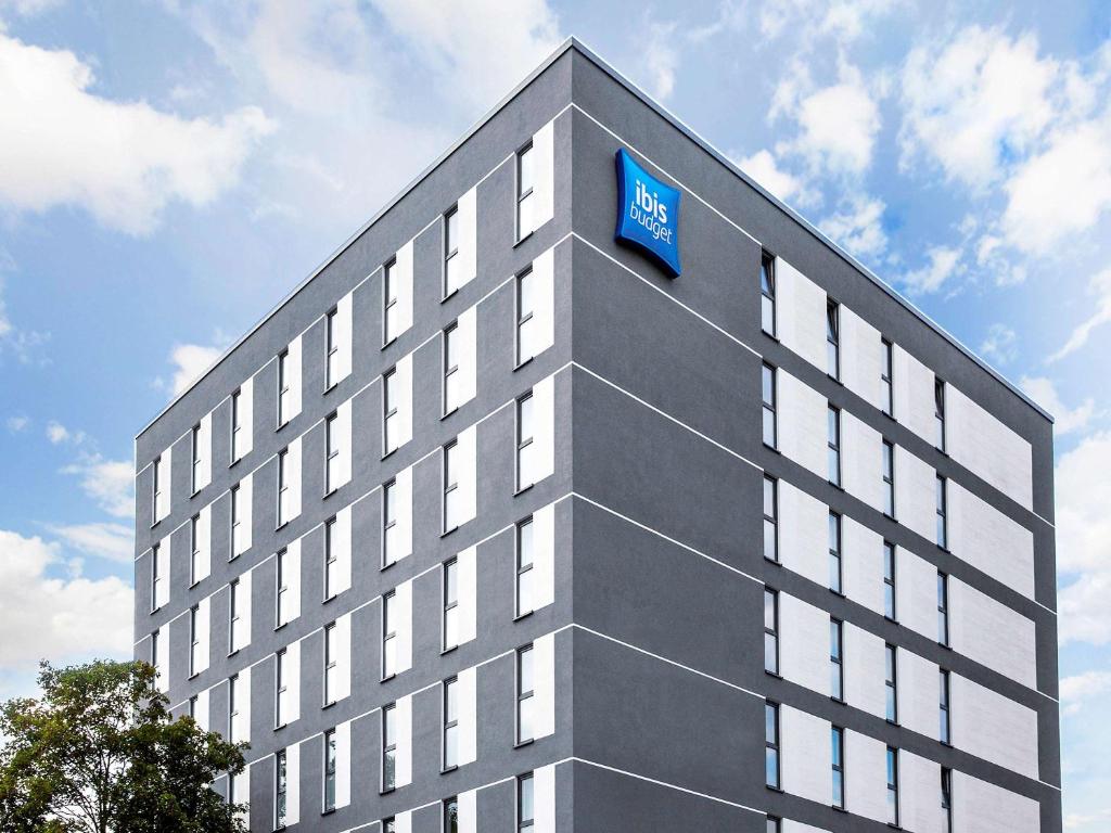 Un bâtiment avec un panneau bleu en haut dans l'établissement Ibis budget Osnabrück City, à Osnabrück