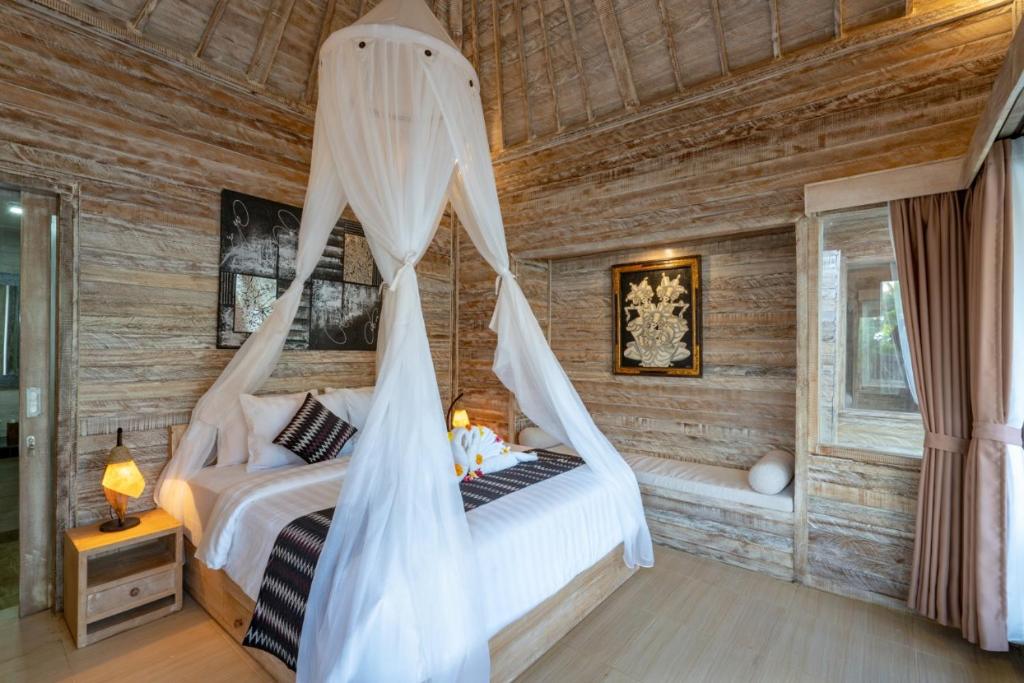 a bedroom with a bed with a mosquito net at Helly's Secret Garden Cottage in Nusa Lembongan