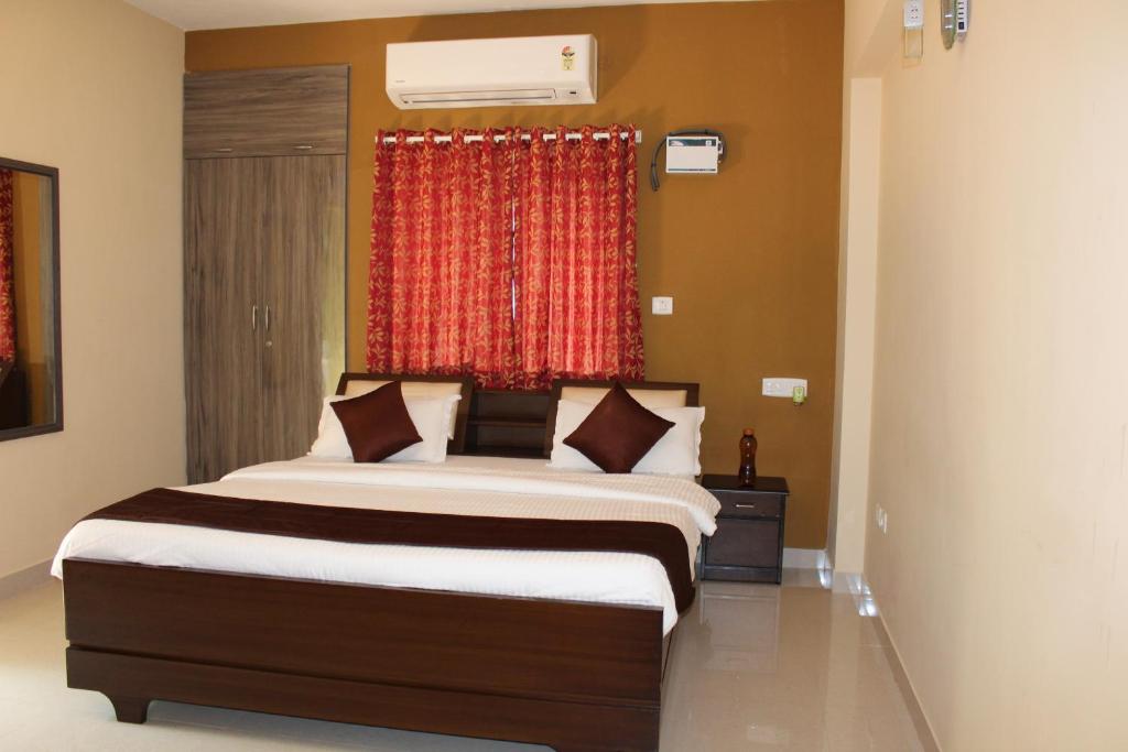 a bedroom with a large bed with a red curtain at Phoenix Serviced Apartment - Sai Illam in Chennai