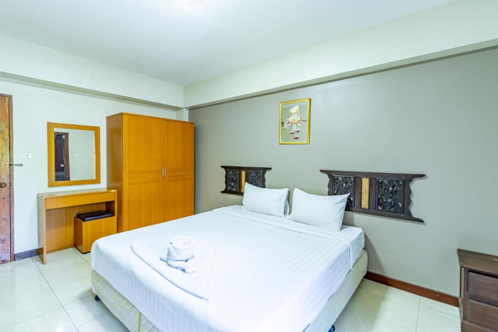 1 dormitorio con cama blanca y armario de madera en Silver Gold Garden, Suvarnabhumi Airport, en Lat Krabang