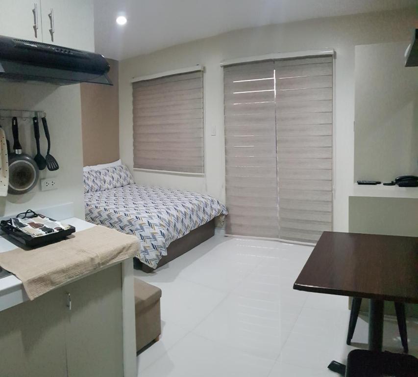 a small room with a bed and a kitchen at Skymagz 314 at Cityscape Residences in Bacolod