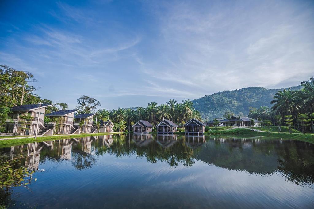 a row of houses on the water with trees at Sementra Hot Spring Nature Resort in Gopeng