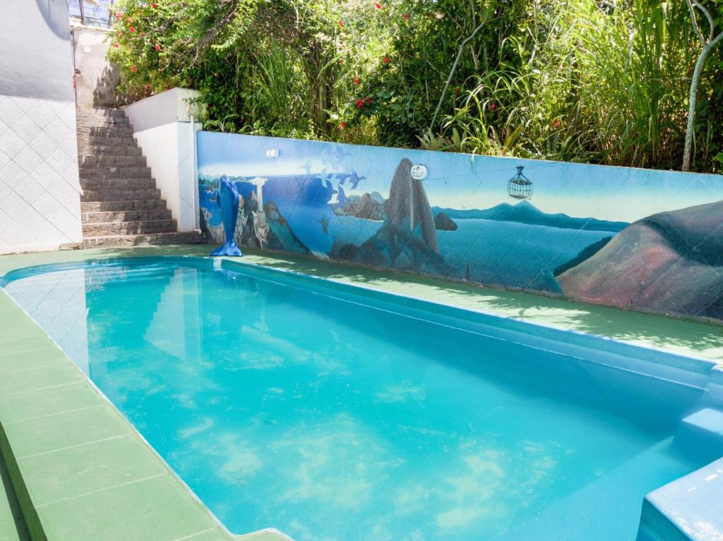 a swimming pool with a mural on a fence at Solares de Maricá in Maricá