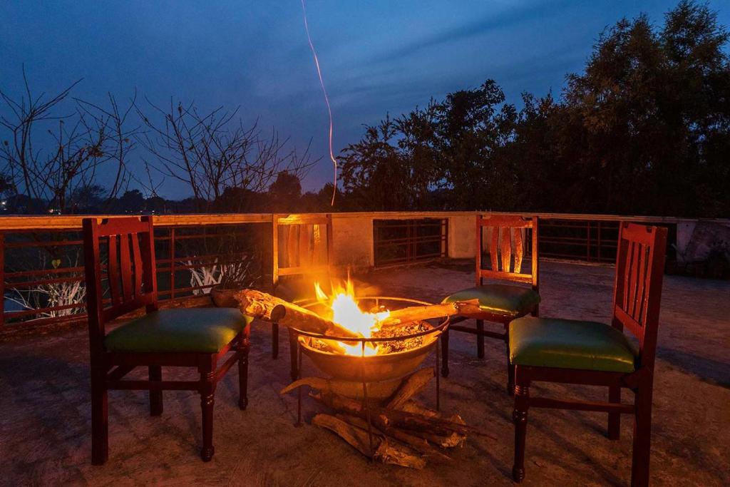 un focolare con sedie e un tavolo con fiamme di The Rangers Lodge, Imran's Jungle Home in Corbett a Ramnagar