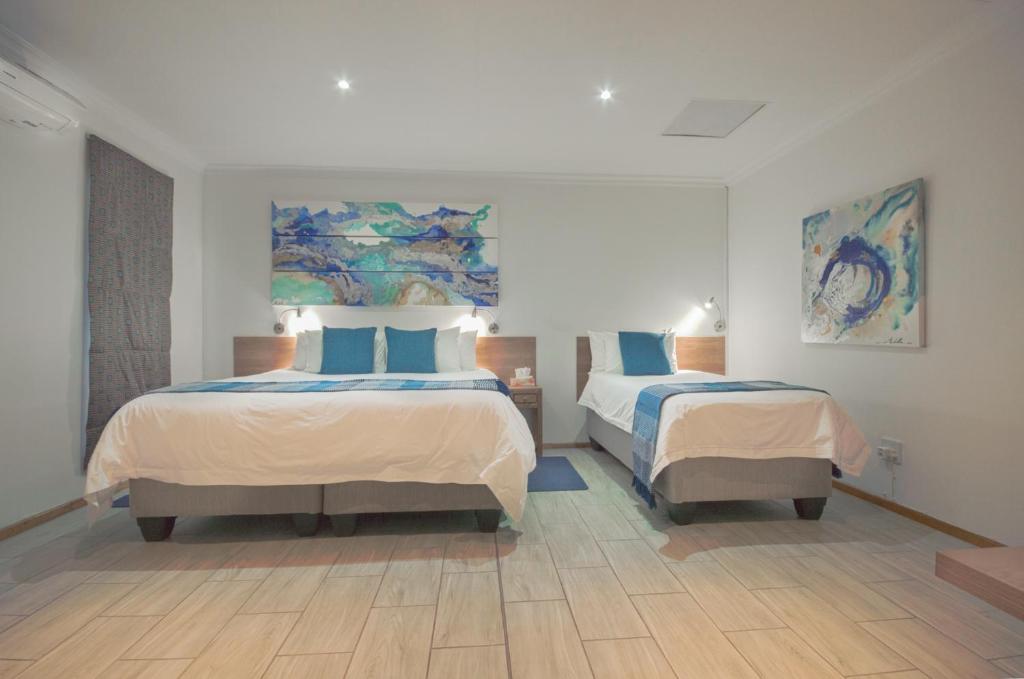1 dormitorio con 2 camas y almohadas azules en President Lodge, en Edenvale