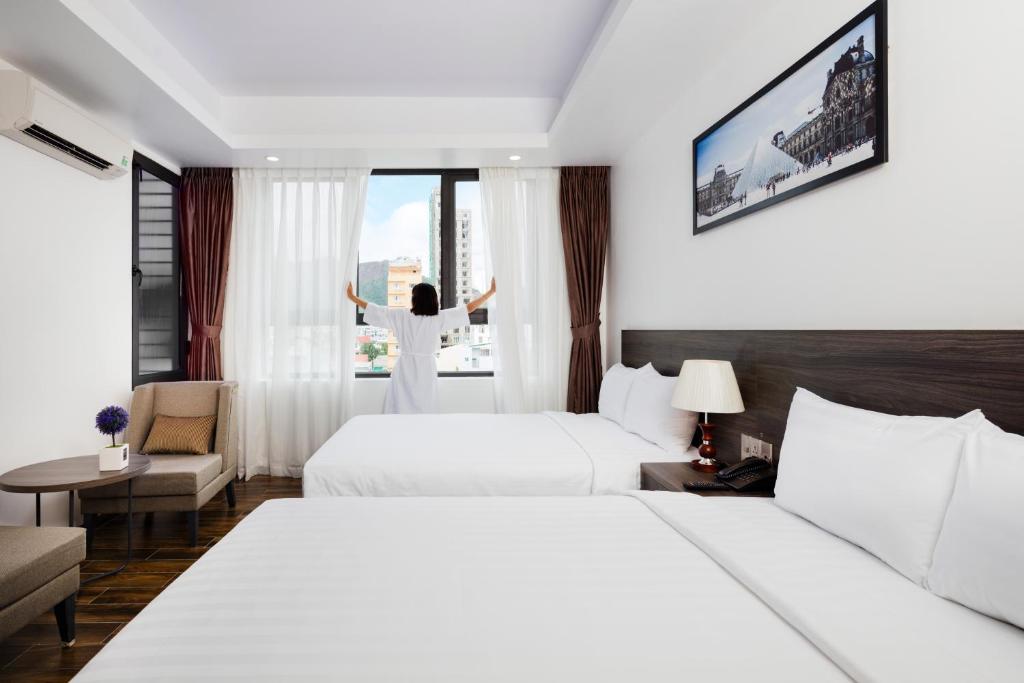 a woman standing in a hotel room with two beds at La Casa Hotel Nha Trang in Nha Trang