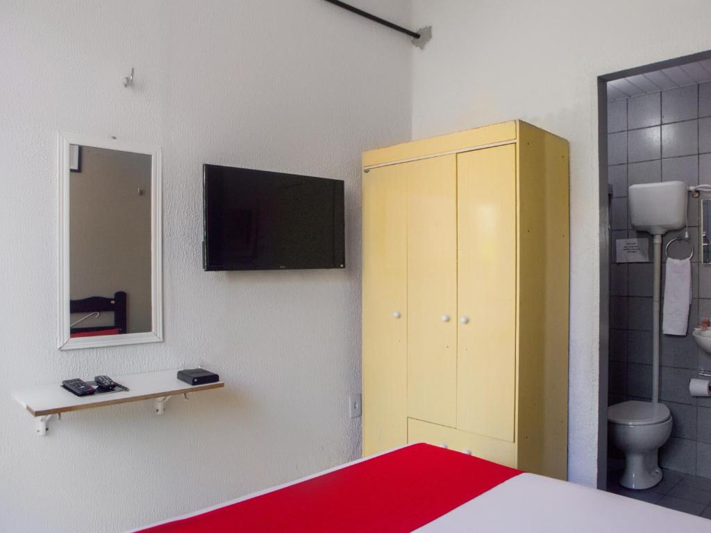 um quarto com uma cama, um armário amarelo e um espelho. em Pousada Atlantico Centro - Fortaleza em Fortaleza