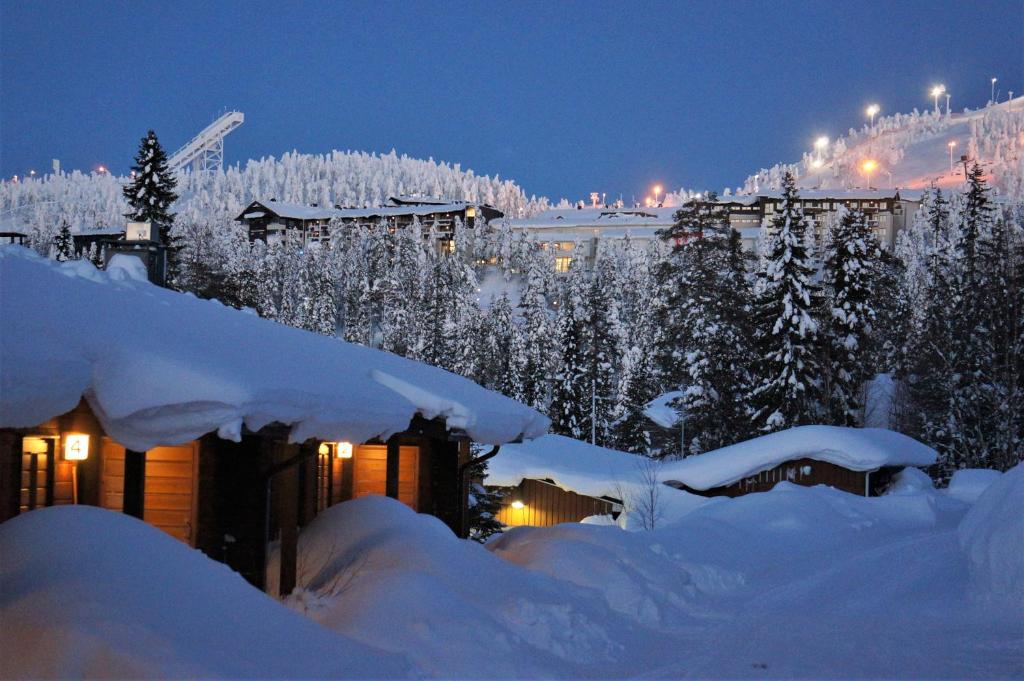 una casa cubierta de nieve por la noche con árboles nevados en Rukariutta Apartments en Ruka