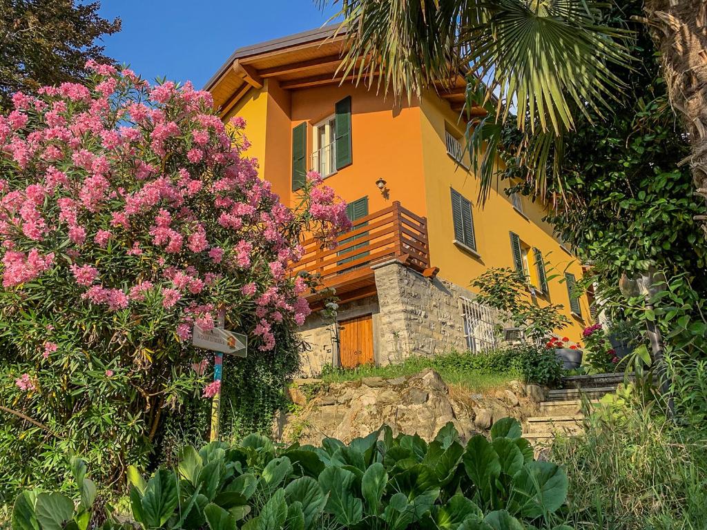 A Casa Di Maria في كومو: منزل أصفر وورود وردية أمامه