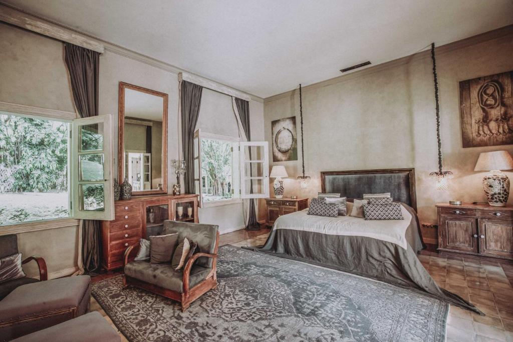 - une chambre avec un lit, une chaise et des fenêtres dans l'établissement Balquisse Heritage Hotel, à Jimbaran