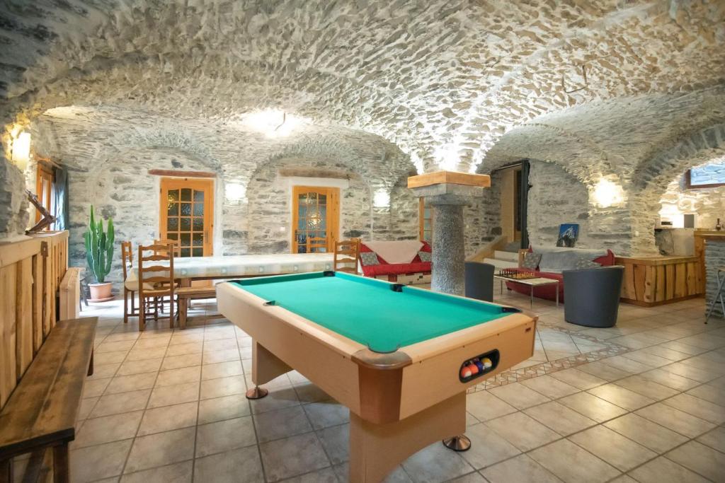 una mesa de billar en una habitación con una pared de piedra en Le Chalet du Villard, en Saint-André