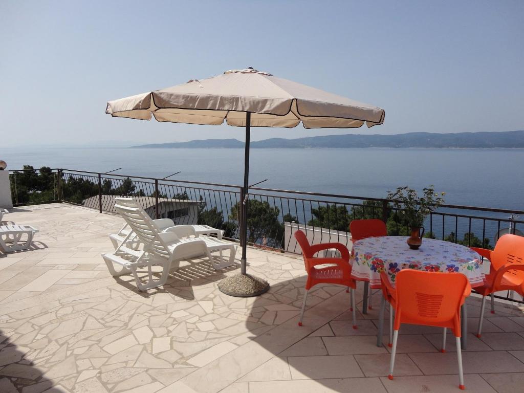 a patio with a table and chairs and an umbrella at APARTMAN LUCIJAN in Marusici 