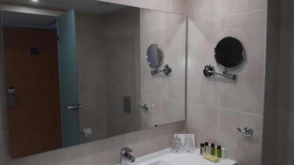 a bathroom with a sink and a large mirror at Karousos Beach Rooms in Ayia Napa