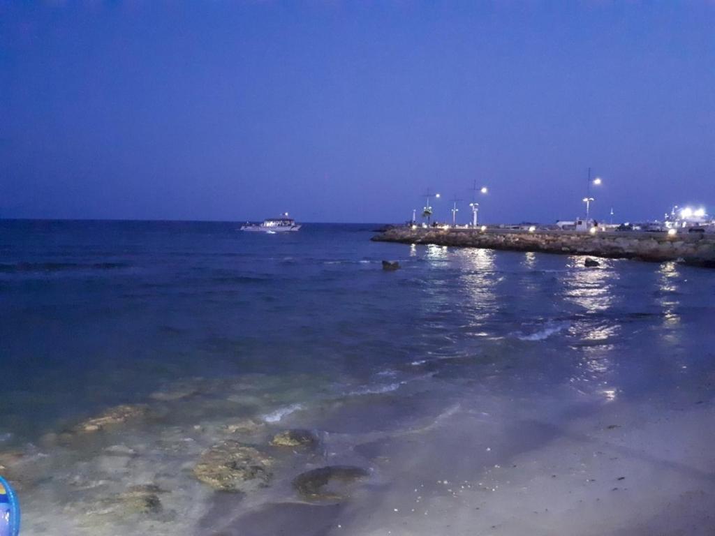 a beach with a boat in the ocean at night at Karousos Beach Rooms in Ayia Napa