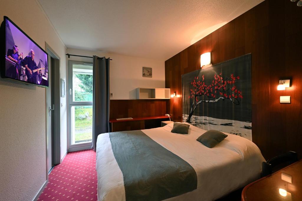 ein Hotelzimmer mit einem großen Bett und einem Fenster in der Unterkunft Logis Hotel Horus Restaurant Les Bruyeres in Langon