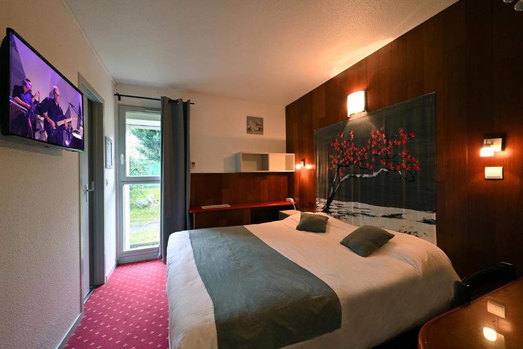 a hotel room with a large bed and a window at Logis Hotel Horus Restaurant Les Bruyeres in Langon