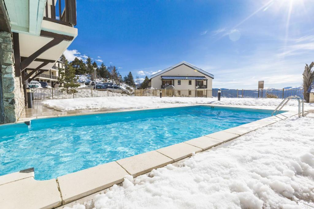 a swimming pool covered in snow in front of a house at Résidence Odalys Mille Soleils in Font-Romeu