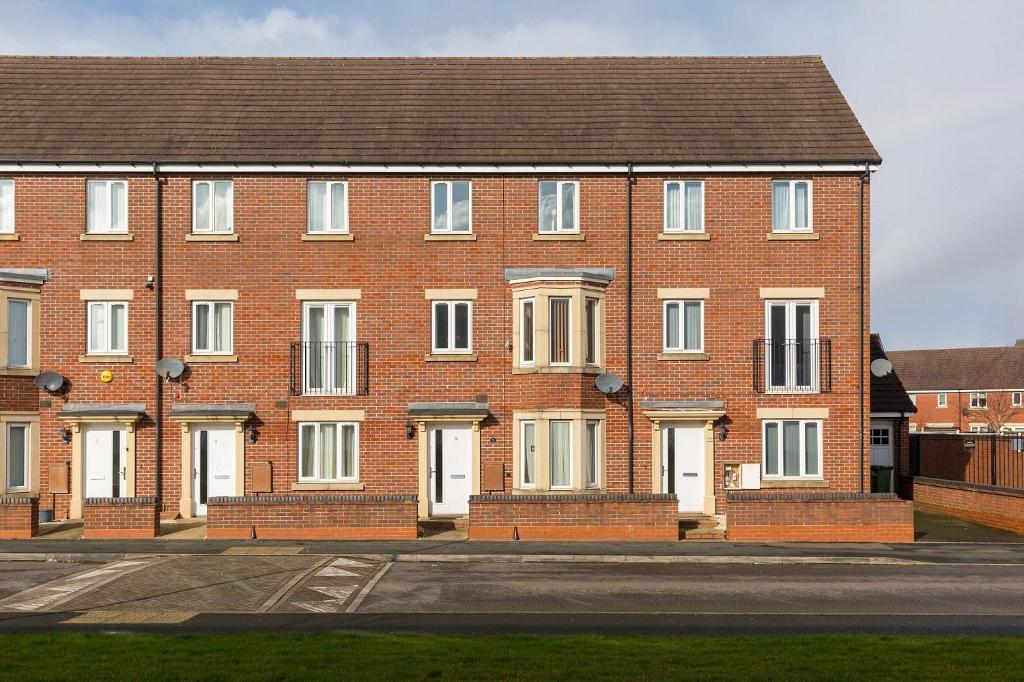 a large brick building with white doors on a street at 6 Bedroom New Build House in Wolverhampton