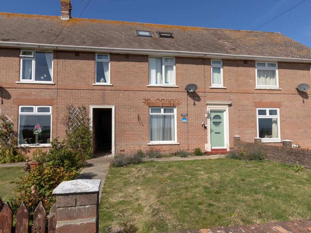 une maison en briques avec une porte verte et une cour dans l'établissement The Lookout -The House With A View, à Weymouth