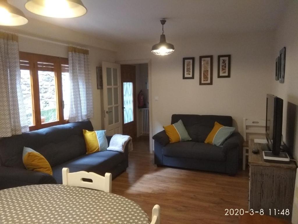 ein Wohnzimmer mit 2 Sofas und einem TV in der Unterkunft Casa Julio in Torla-Ordesa