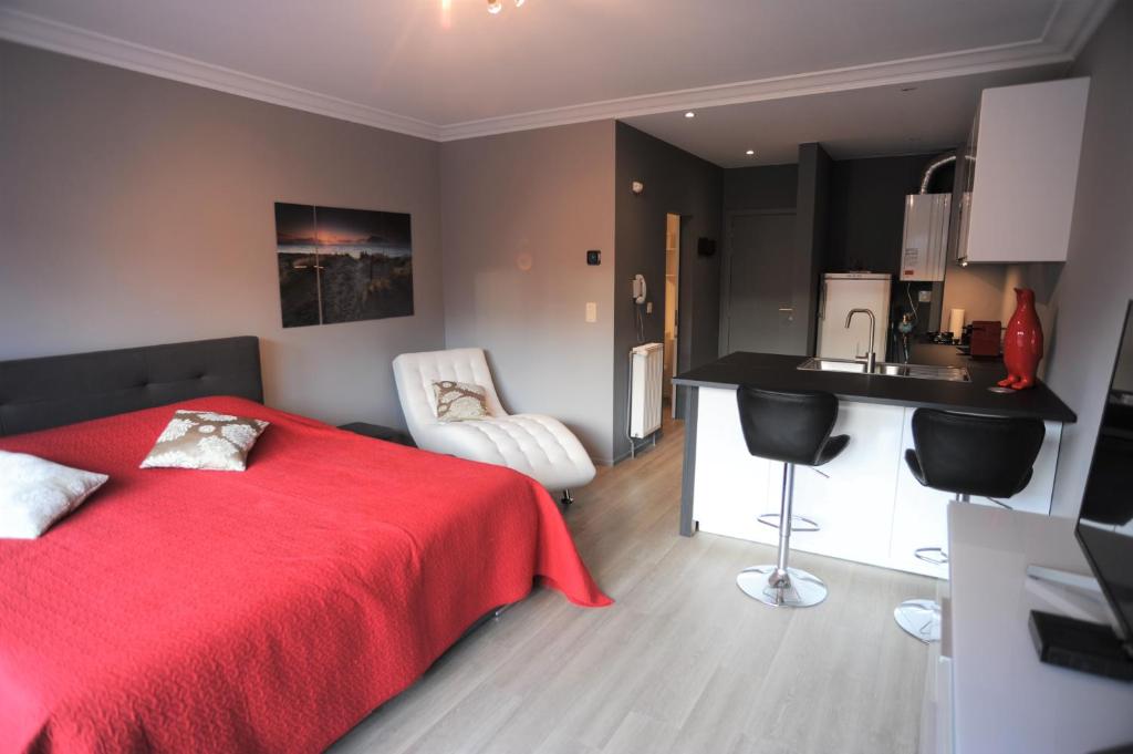a bedroom with a red bed and a kitchen at Knokke Modern Studio in Knokke-Heist