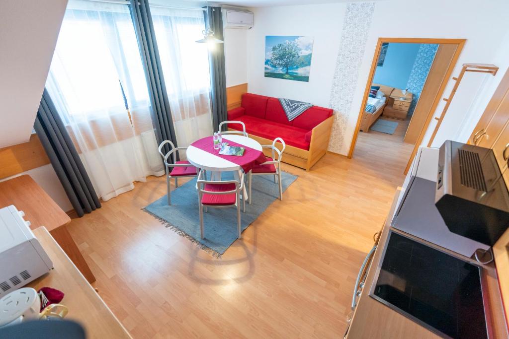- un salon avec une table et un canapé rouge dans l'établissement TD Bohinj Apartments, à Bohinj