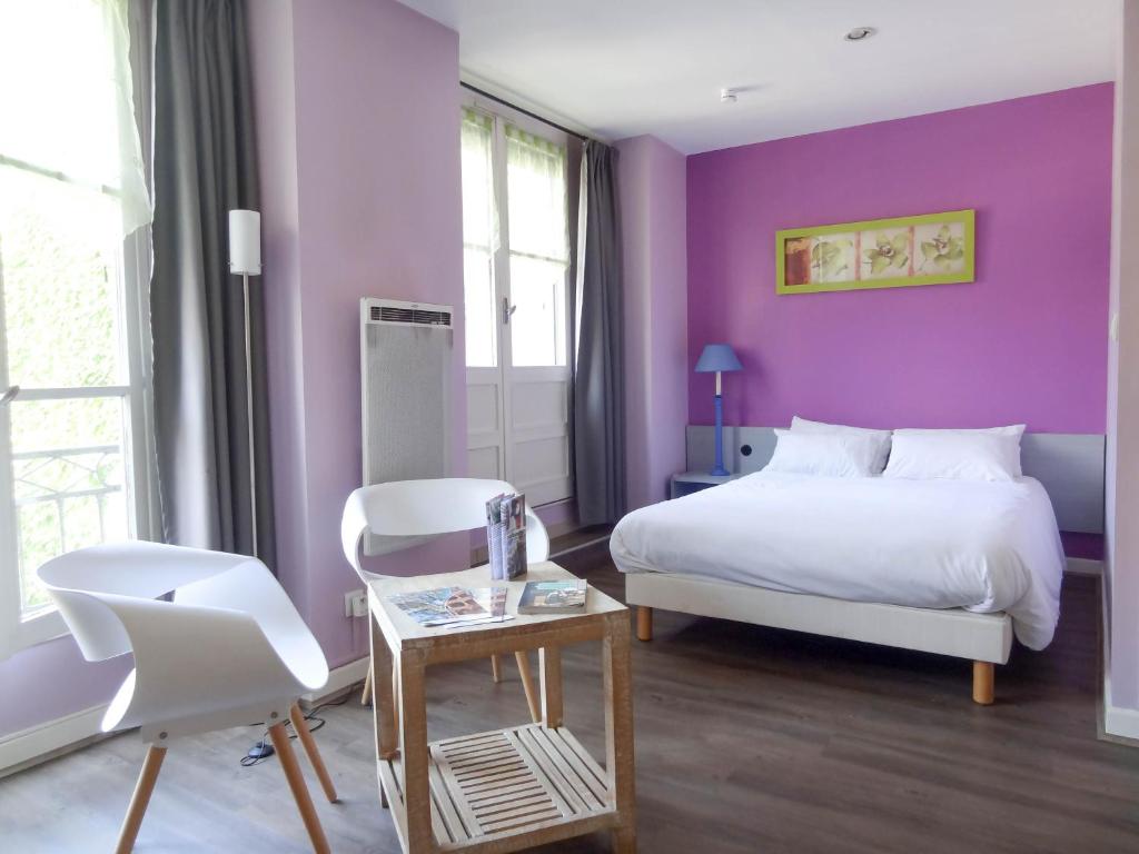 リヨンにあるアヴィ レジデンス リヨン ベルクールの白いベッドと紫の壁が備わるベッドルーム1室