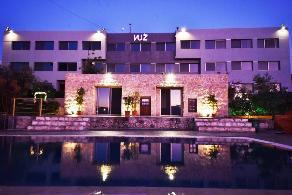 un edificio con una piscina delante de él por la noche en VU'Z Hotel, en Biblos