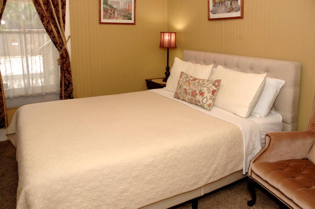 a bedroom with a large white bed and a chair at Quaint Historic Downtown Apartment in St. Augustine