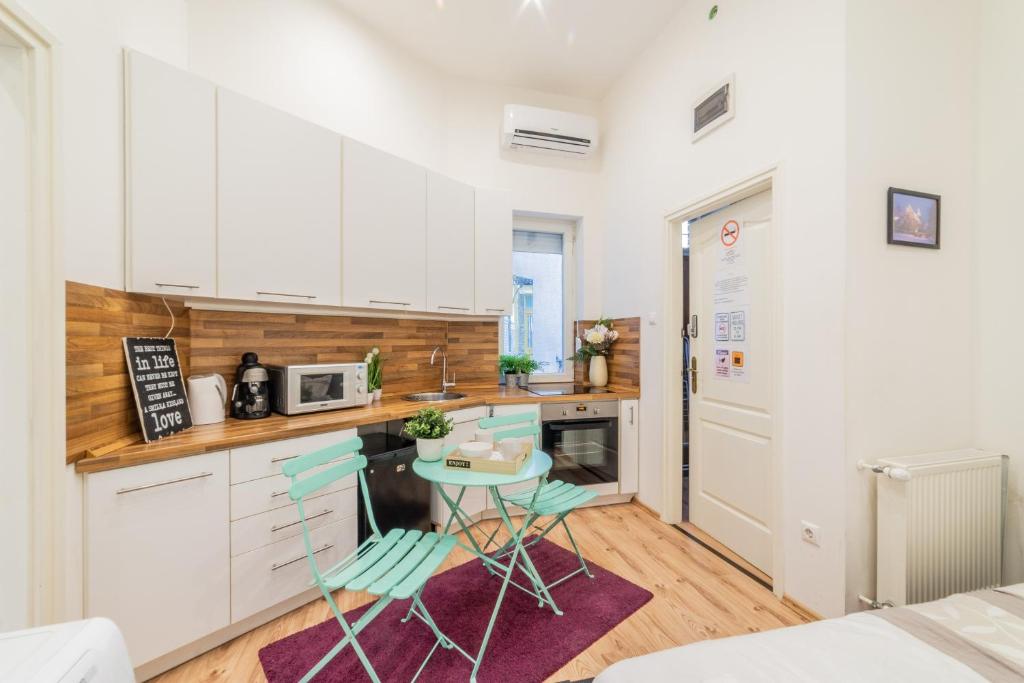 ブダペストにあるReal Apartments Anker IIの白いキャビネット、テーブルと椅子付きのキッチンが備わります。