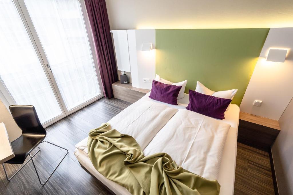 a bedroom with a large bed with purple pillows at Hotel Demas City in Munich