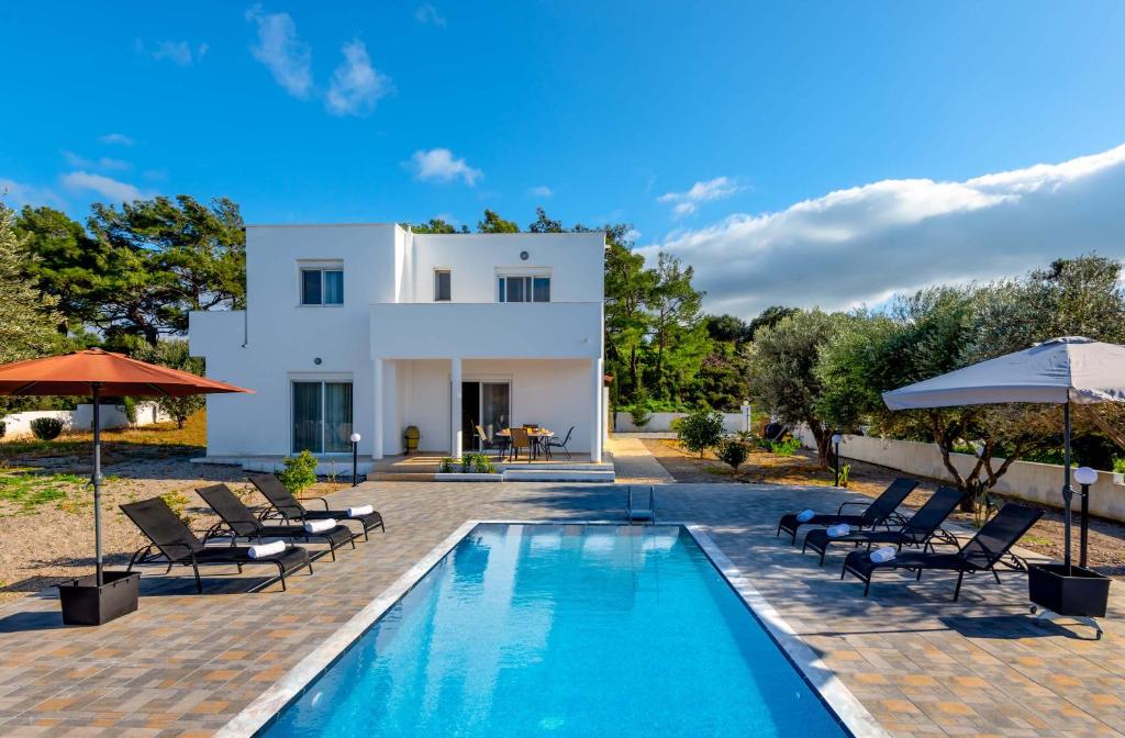 a villa with a swimming pool with chairs and umbrellas at Vasilis Villa in Fánai