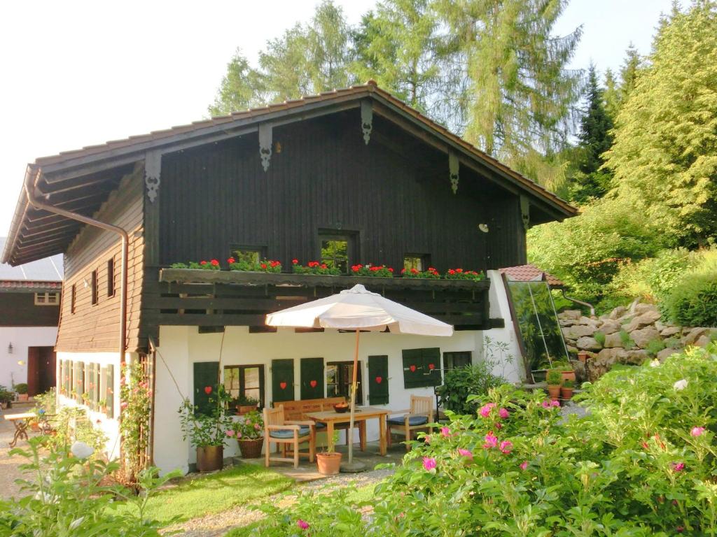 AchslachにあるCosy holiday home in Kollnburg with gardenのテーブルと傘と花の家
