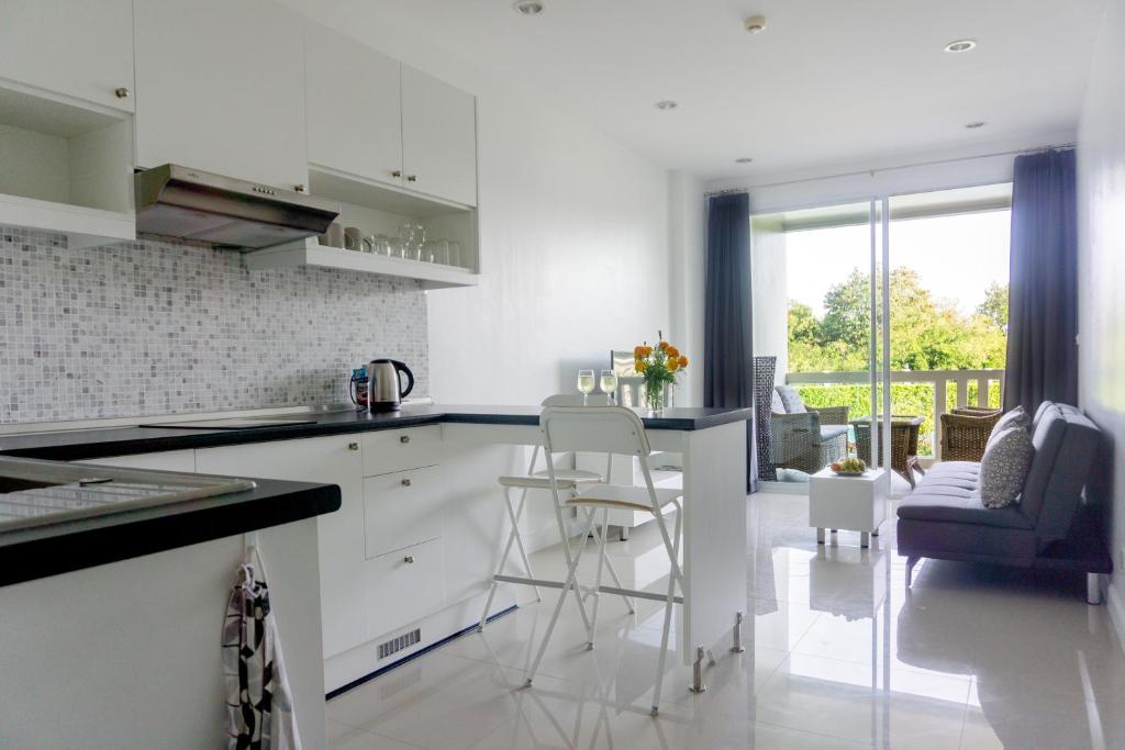 a kitchen with white cabinets and a counter with stools at Lägenhet i Blue Marin. Huay Yang, Thailand in Ban Huai Yang