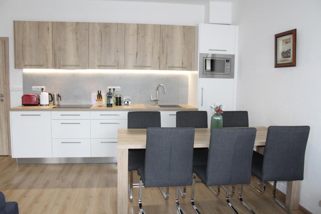 kuchnia z drewnianym stołem i czarnymi krzesłami w obiekcie Apartmán Lipno G11 w mieście Frymburk