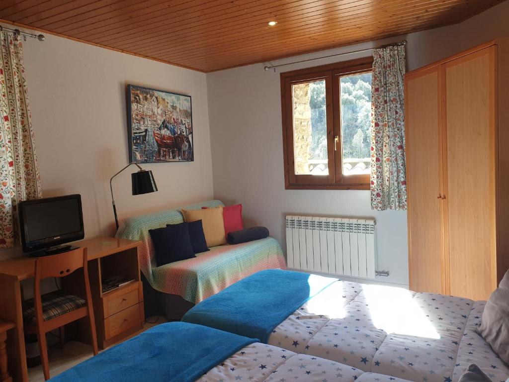 a bedroom with a bed and a desk and a television at Hostal El Forn in Beget