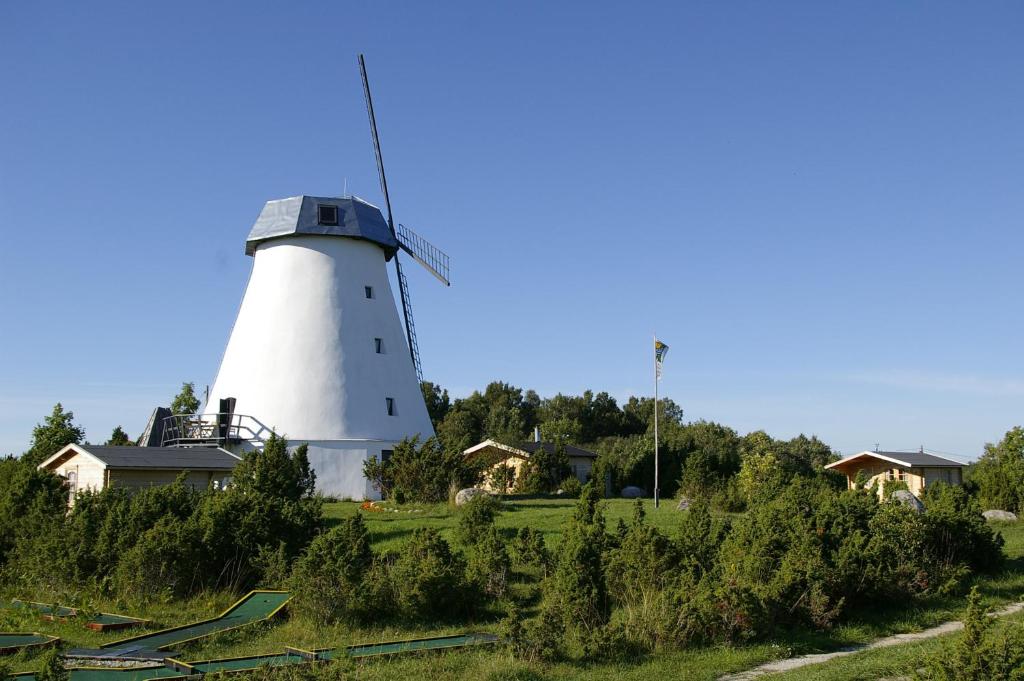 un moulin à vent dans un champ avec une maison dans l'établissement Pivarootsi Windmill, à Pivarootsi