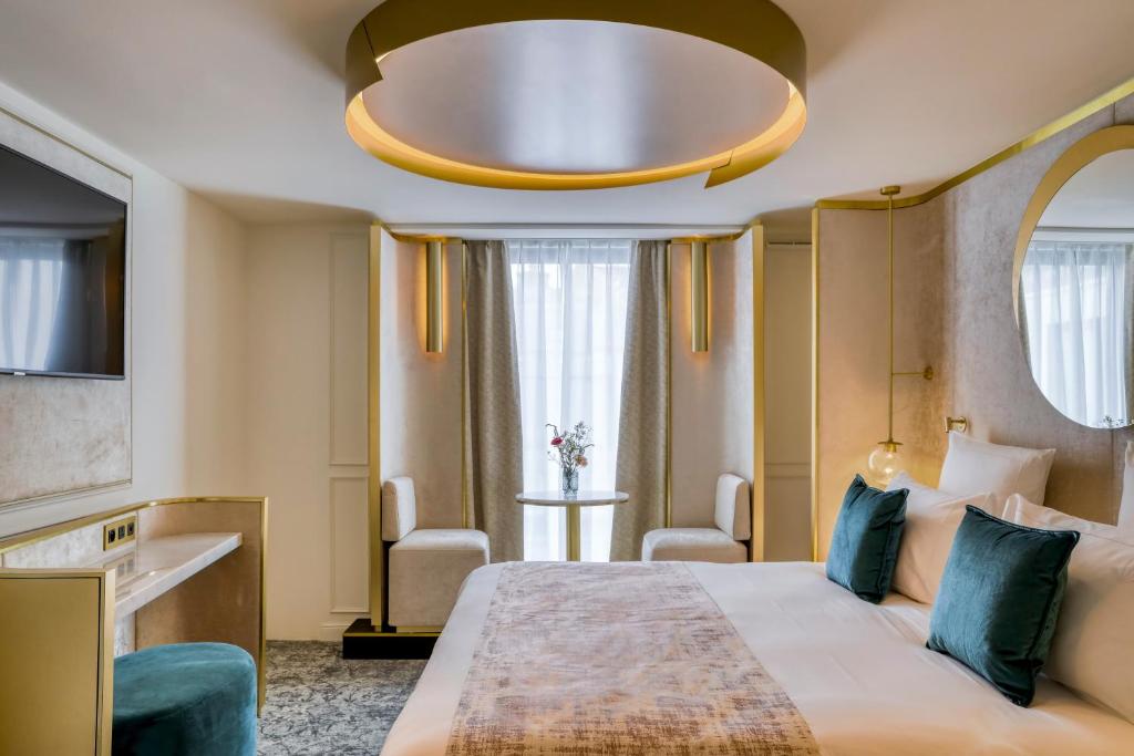 a hotel room with a large bed and a large chandelier at Maison Albar - Le Vendome in Paris