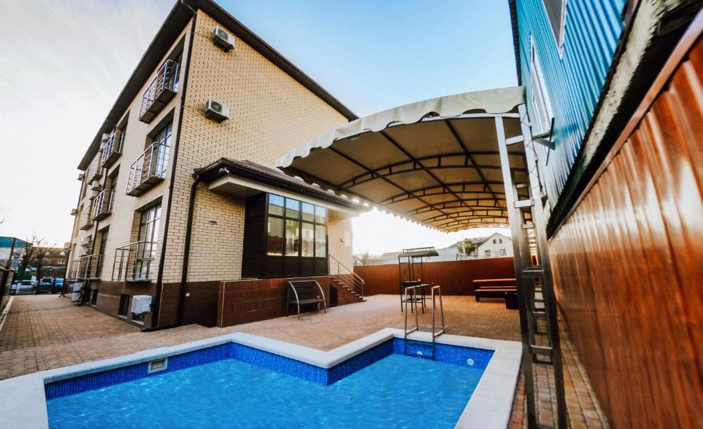 a house with a swimming pool next to a building at Hotel Orion Plus in Anapa