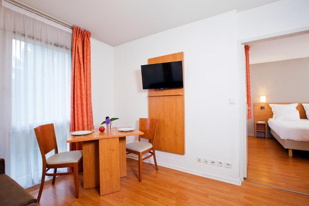 a hotel room with a bed and a table and chairs at Séjours &amp; Affaires Nantes La Beaujoire in Nantes