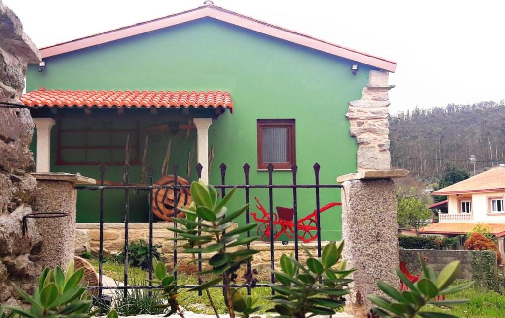 une maison verte avec une clôture devant elle dans l'établissement Casa do Maestro - Costa da Morte, à Vimianzo