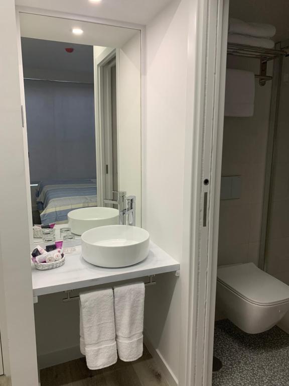 a bathroom with a sink and a toilet and a mirror at Nerja Casual Rooms in Nerja