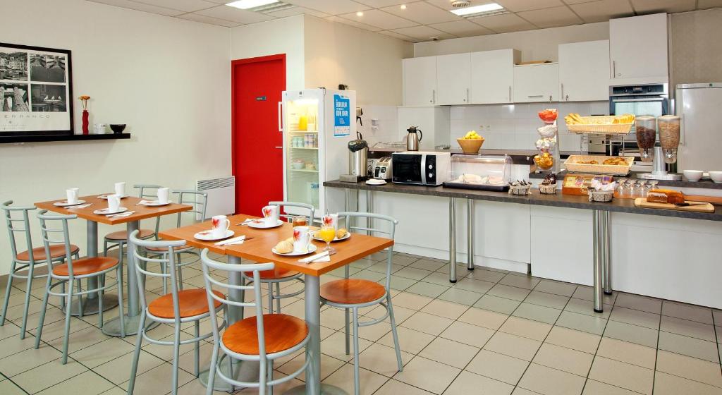 a kitchen with two tables and a refrigerator at Séjours &amp; Affaires Nantes La Beaujoire in Nantes