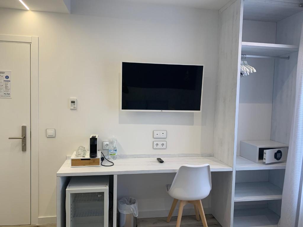 a white desk with a chair and a tv on a wall at Nerja Casual Rooms in Nerja
