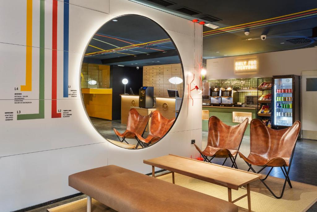 a mirror on a wall with chairs and a table at B&B HOTEL Castellón in Castellón de la Plana