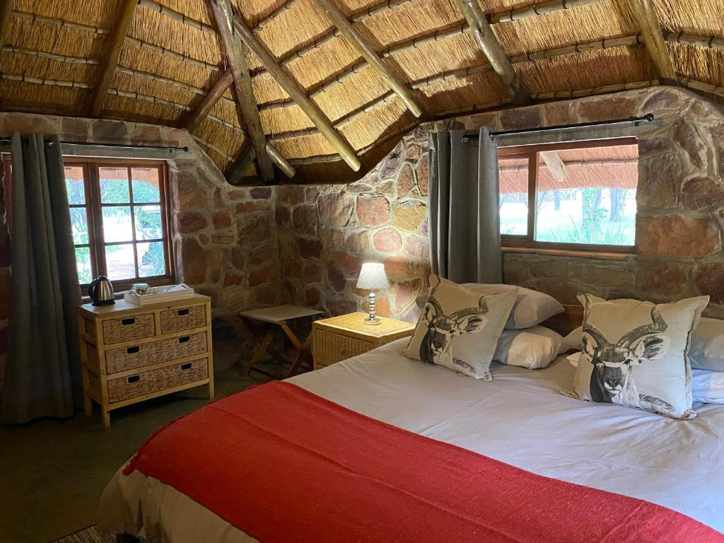 ein Schlafzimmer mit einem großen Bett in einem Zimmer mit Fenstern in der Unterkunft Shondoro Mountain Retreat in Vaalwater