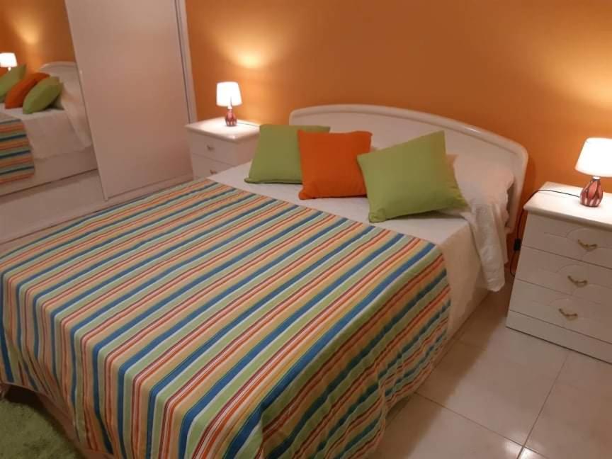 um quarto com uma cama com almofadas coloridas em Casa Nuno em Lagoa